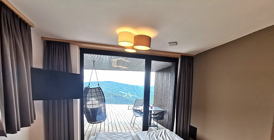 Panorama Living Dolomites: Blick vom Schlafzimmer auf die Terrasse und Bergwelt