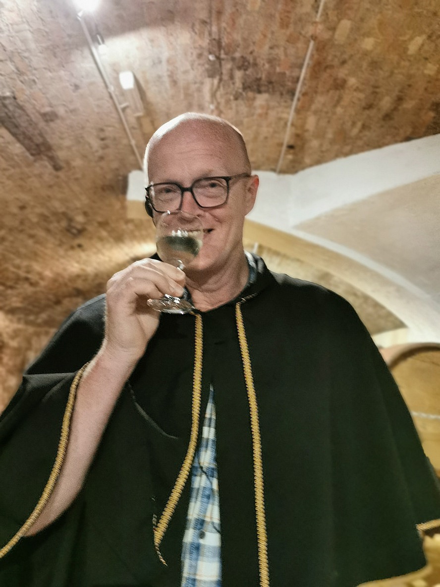 nicko cruises: Axel probiert einen Wein in Tunnelgewölben von Borváros Budafok. Der Umhang wird hier jedem Besucher angezogen