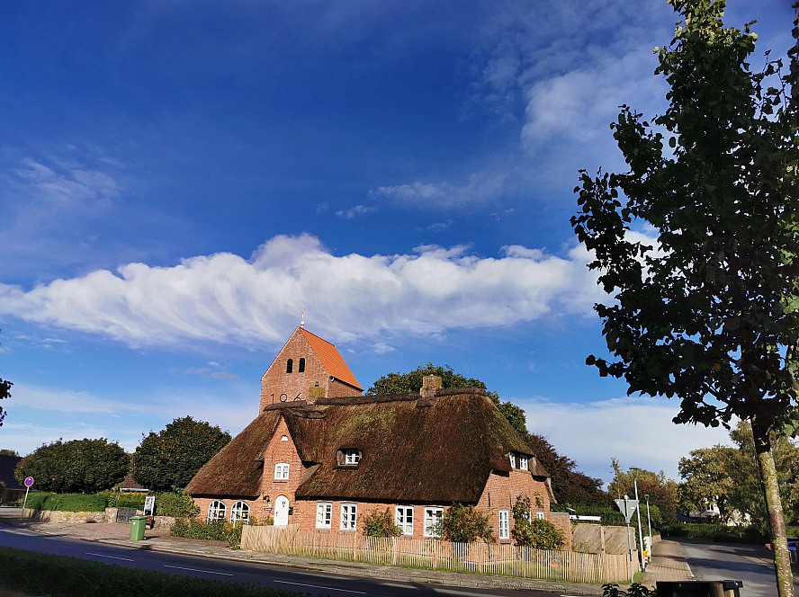 Landhafen Niebüll: gegenüber des Hotels liegen ein malerisches Haus mit Reetdach und eine Kirche